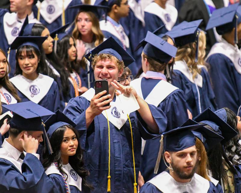 An Oswego East graduate records the moments after finding his seat during the commencement ceremony Saturday May 17, 2025, held at the Convocation Center in DeKalb.