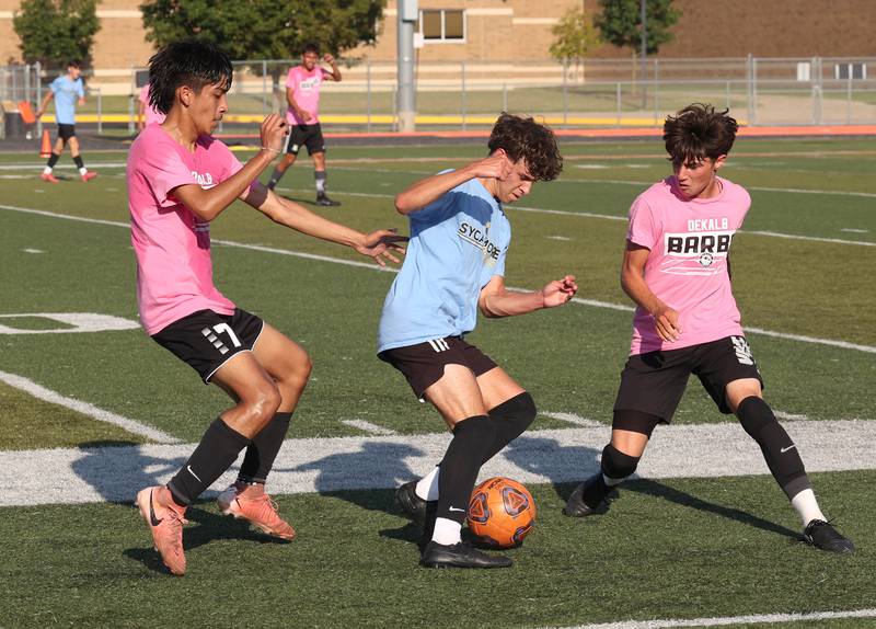 Sycamore’s Noah Daykin works between two DeKalb defenders Monday, July 14, 2025, during a summer boys soccer friendly at DeKalb High School.