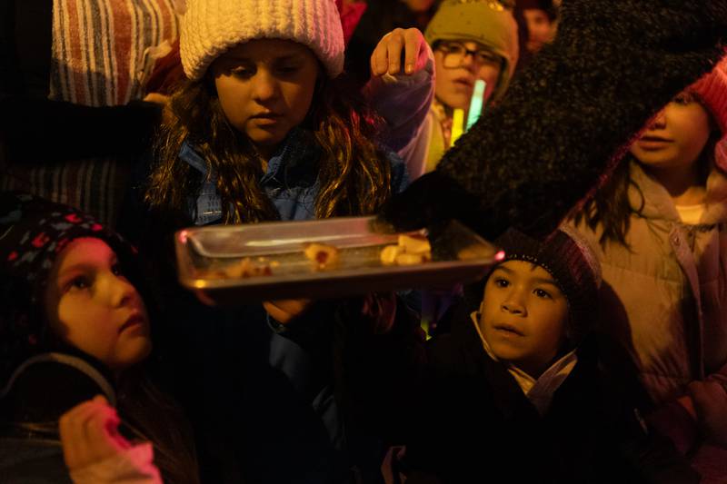 Kids grab pieces of candy cane from Graham's Fine Chocolates and Ice Cream's old-fashioned candy cane pull during the Annual Geneva Christmas Walk on Friday, Dec. 5, 2025.