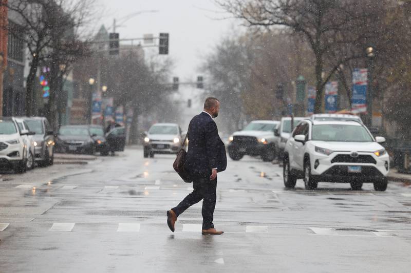 A pedestrian crosses Ottawa Street as light snow falls on Tuesday. The National Weather Service issued a Winter Weather Advisory from Tuesday until early Wednesday with snow accumulations of 1 to 3 inches expected throughout Will County.