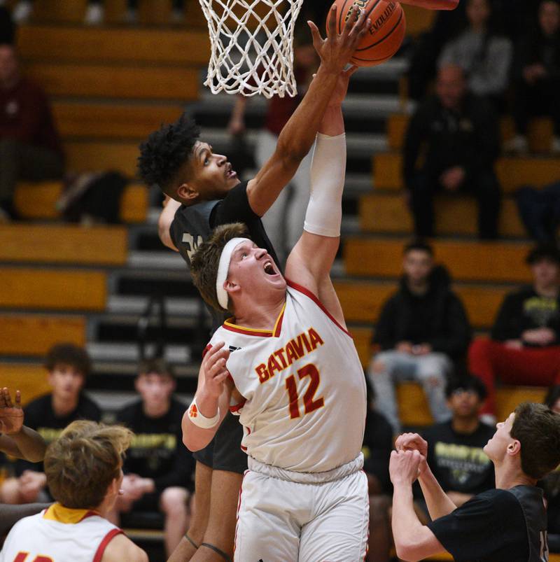 Batavia's J.P. Chaney (12) stretches for a rebound with Glenbard North's JJ Hernandez during Tuesday’s boys basketball game in Batavia.