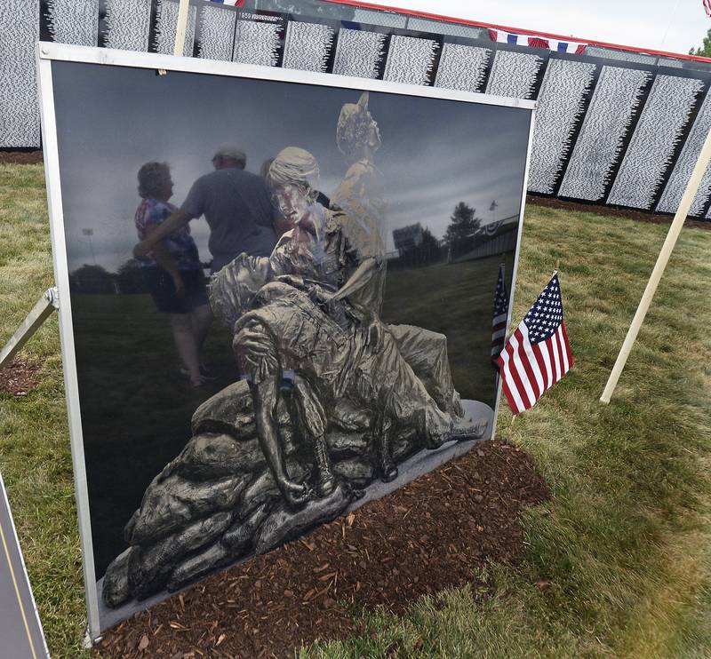 A couple of visitors to the Vietnam Traveling Memorial Wall are reflected in a monument Saturday, Aug. 26, 2023, at Veterans Memorial Park in Peru prior to a ceremony honoring those who are on the wall.