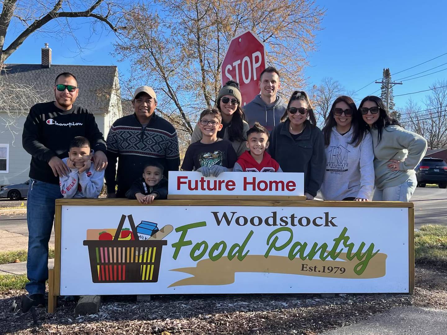 Woodstock Food Pantry volunteers pictured by a sign announcing the future home of the food pantry in Woodstock in Nov. 2025.