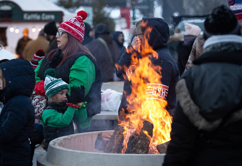 Everly Lancaster, 5, left, of Manteno, warms her hands while out with her mom, Kali Lancaster, background, at the Manteno Christmas celebration on Saturday, December 6, 2025.