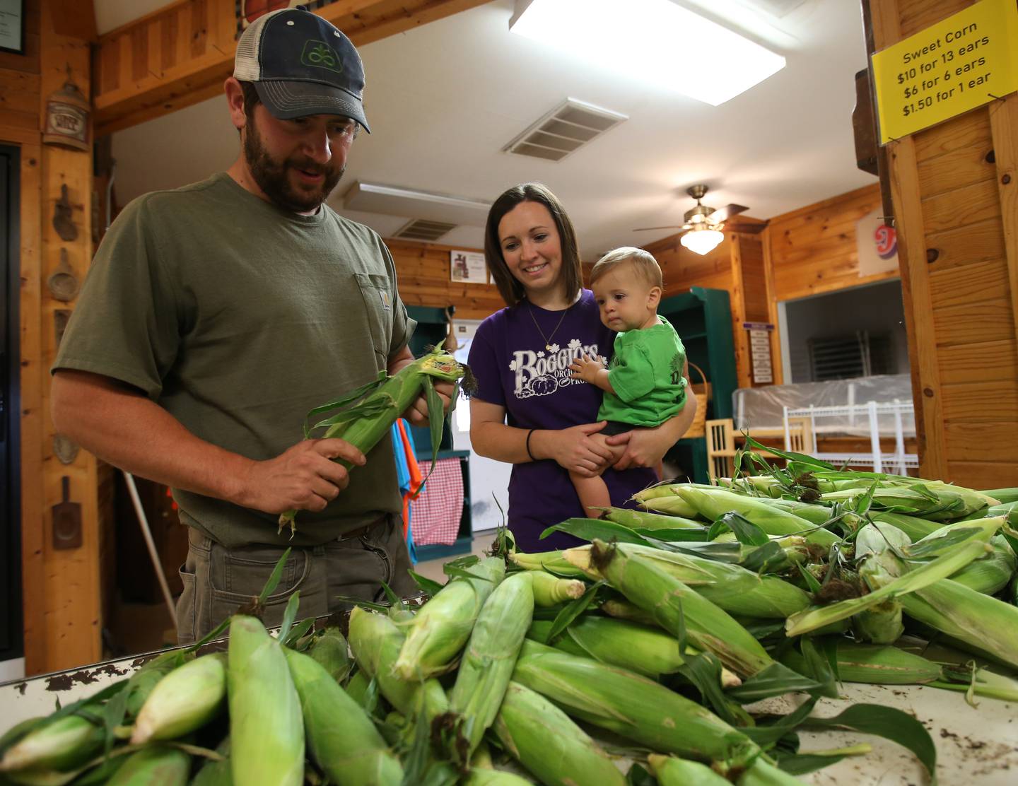 Joe and Christine Migliorini along with their son Geo peal sweet corn at Boggios Orchard and Produce on Wednesday, July 19, 2023 in Granville. The couple bought the orchard this year from Keith and Denise Boggio after 30 years of operation. Joe is a nephew of Keith and Denise. He, along with his wife, look forward to keeping the operation in the Boggio family while continuing to provide the same great experience that Keith, Denise, and their family have worked hard to build and you have grown to love.