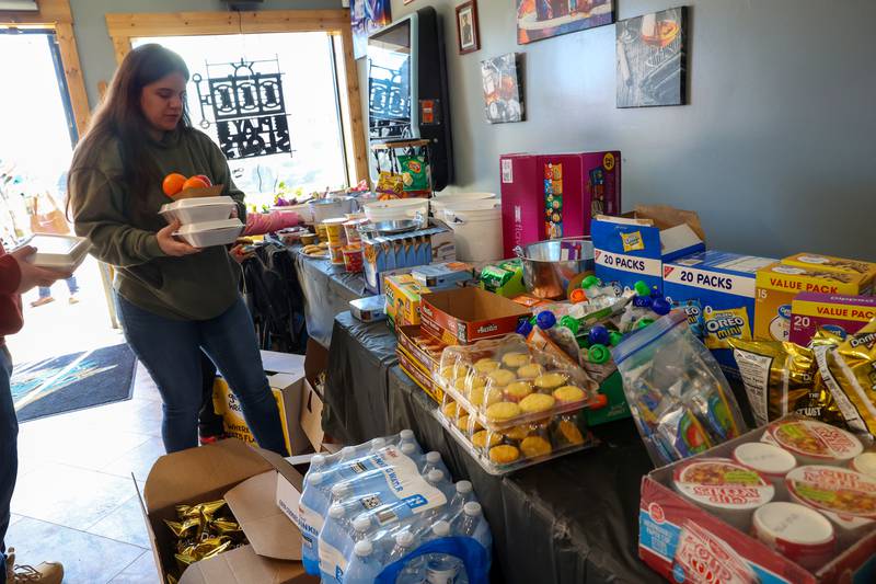 Sarah Brandenburg, of Aroma Park, picks up meals at the Fun Hub on March 12, 2026. The small bar transformed into a bustling hub of supplies, food and resources following the March 10 tornado that caused destruction in Aroma Township and across Kankakee County.