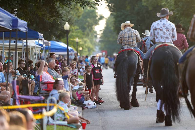 Paradegoers watch as horses ride down the street during the 87th Momence Gladiolus Festival Main Street Parade on Friday, Aug. 8, 2025.