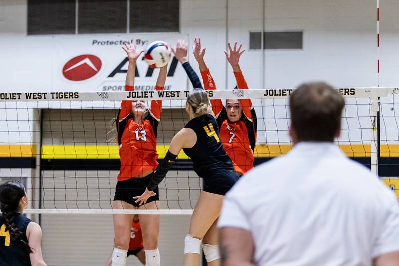 Joliet West's Lina Govoni hits as Lincoln-Way West's Emma Novotny and Kara Stigter go up to block during a varsity volleyball game at Lincoln-Way West on Sept. 15, 2025.