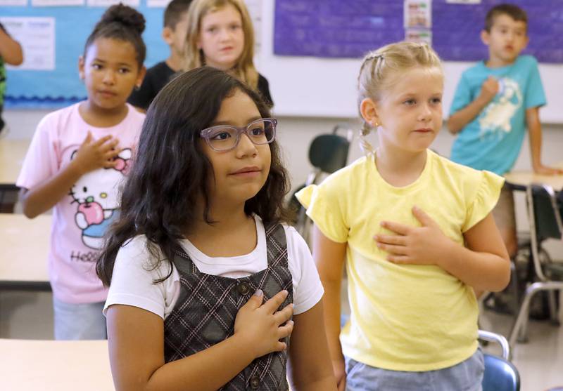 Second grader’s Ayari Plascenncia and Austin Romme, say the “Pledge of Allegiance” with other students in Teddi Salas second grade dual language classroom on the first day of school, at Olson Elementary School in Woodstock, on Aug. 14, 2024.