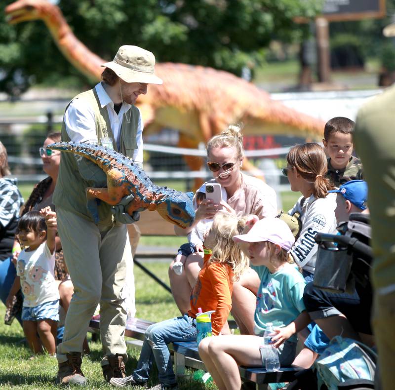 Ashton Cox carries a baby dinosaur during a dinosaur training session as part of the Dino Farm Adventure at Kuipers Family Farm in Maple Park on Thursday, May 30, 2024. The Dino Farm Adventure will be at Kuipers until June 16.