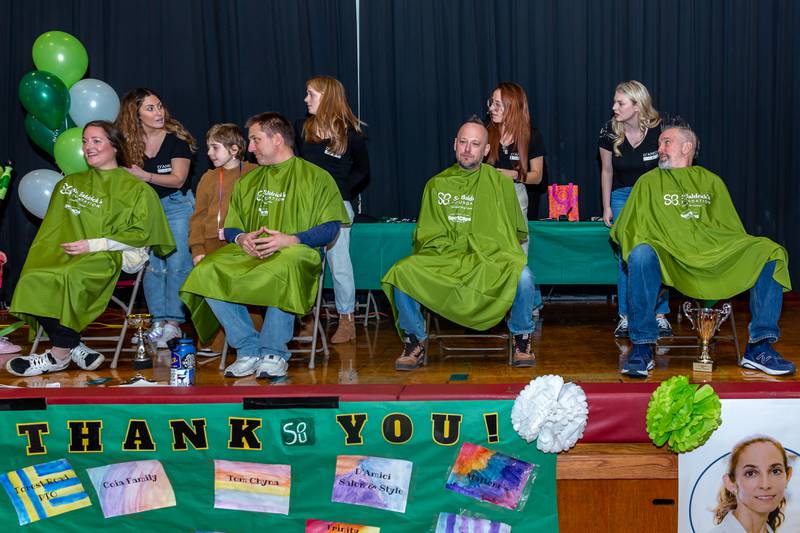 Gwen's parents Hilary and A.J. from the left, on stage to get their hair cut at the St Baldricks Foundation event for Gwen Cola at Forest Road Elementary School in La Grange Park. March 23, 2023.