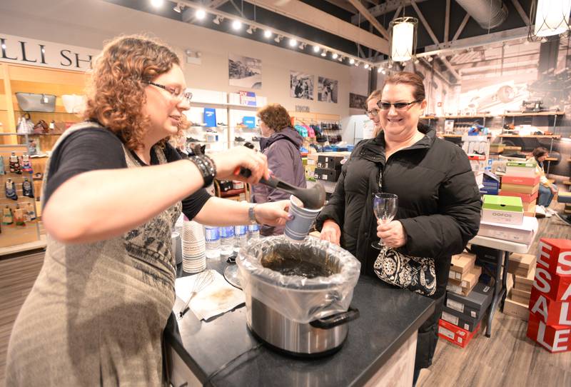Miroballi Shoes staff (left) Cari Malhall serves hot cider to designated drivers and others including Janet Foss of Streamwood  during the Winter Wine and Cheese Walk in Wheaton Saturday, Feb 3, 2024.