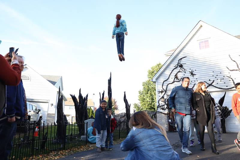 Suni Mansilla, who came from Chicago, takes a photo of her kids Marissa and Nathan with the levitating Max. The Plainfield Halloween display based on the Netflix show "Stranger Things" has gone viral on social media. Saturday, Oct. 8, 2022, in Plainfield.