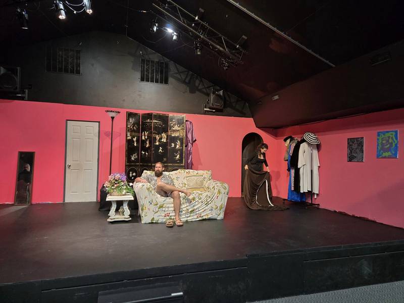 Matt Pasternak, playing Thomas sits on a couch on stage while performing.