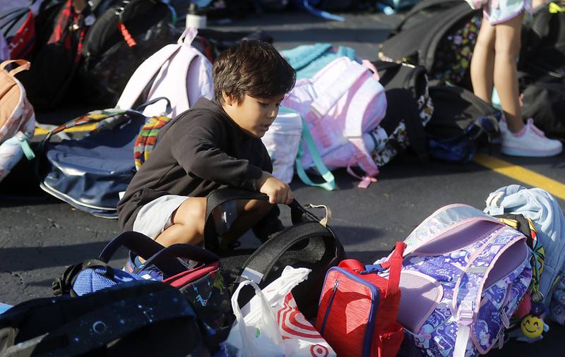 Second grader Isaac Suarez, 7, adds his backpack to classroom pile on the first day of school at West Elementary School in Crystal Lake on Wednesday, Aug. 16, 2023.