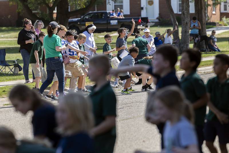 School kids from local Catholic schools scoop up candy Friday, Sept. 12, 2025, during Newman High School’s homecoming parade.