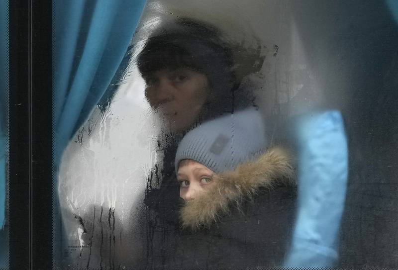 A woman and child peer out of the window of a bus as they leave Sievierodonetsk, the Luhansk region, eastern Ukraine, Thursday, Feb. 24, 2022. Russian President Vladimir Putin on Thursday announced a military operation in Ukraine and warned other countries that any attempt to interfere with the Russian action would lead to "consequences you have never seen." (AP Photo/Vadim Ghirda)