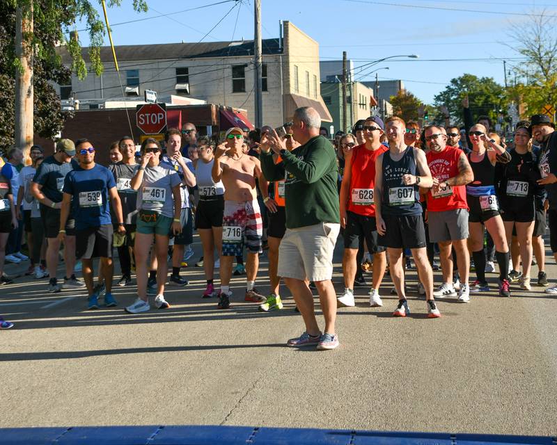 DeKalb Mayor Cohen Barnes takes a selfie with DeKalb Corn Classic 5K runners before the start of the race on Sunday, Sept. 29, 2024 held in downtown DeKalb.