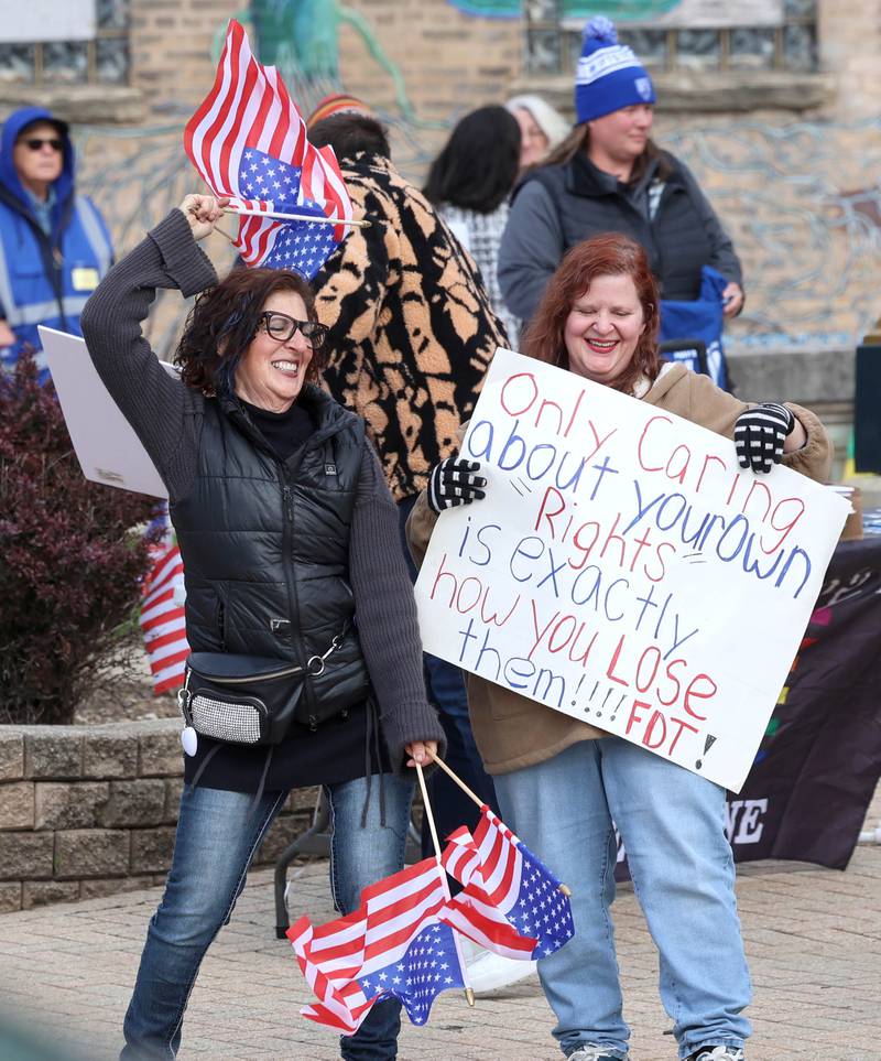 Protesters hold signs and wave flags Friday, May 1, 2026, during a May Day rally at Memorial Park in downtown DeKalb. The group gathered to advocate for workers’ rights and push for billionaires to be taxed amid cost-of-living burdens they argue are hurting everyday Americans.
