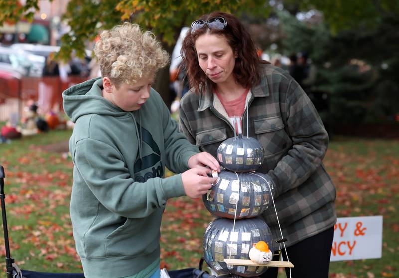 Parker Nelson, (left) 12, and his mom Hillary, from Sycamore, put the finishing touches on his pumpkin skyscraper Wednesday, Oct. 22, 2025, during opening day of the Sycamore Pumpkin Festival.