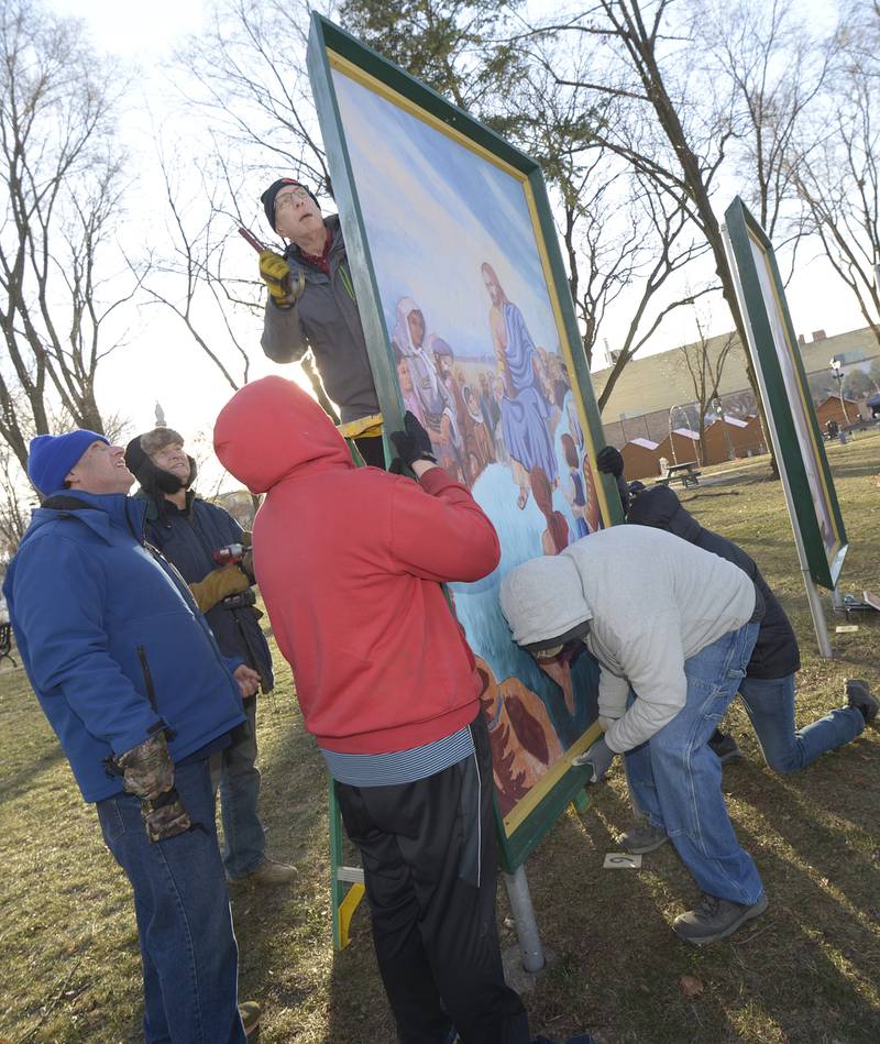 Volunteers lift to install 1 of the 16 paintings depicting the life of Christ Saturday in Ottawa’s Washington Square.The 4-foot by 7-foot paintings. The Ottawa Freedom Association has erected the paintings each year since 1992 after winning a lengthy court battle.