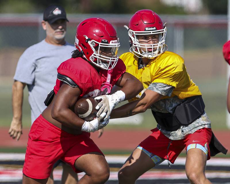 T.J. Harland takes the handoff from Jack Beetham at Yorkville High School football practice, Monday, Aug 13, 2025  in Yorkville.