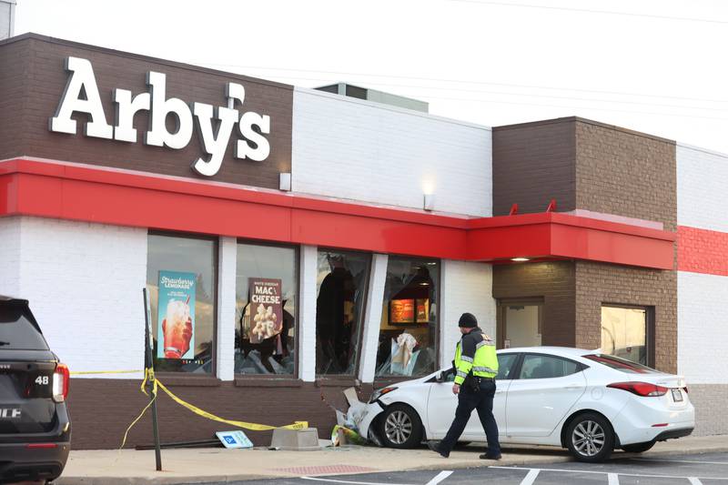 Peru Police officer Brad Anderson, secures the scene with caution tape after a car stuck the Arby's building on Friday, Dec. 19, 2025 in Peru. The incident happened shortly after 3:30p.m. No injuries were reported.