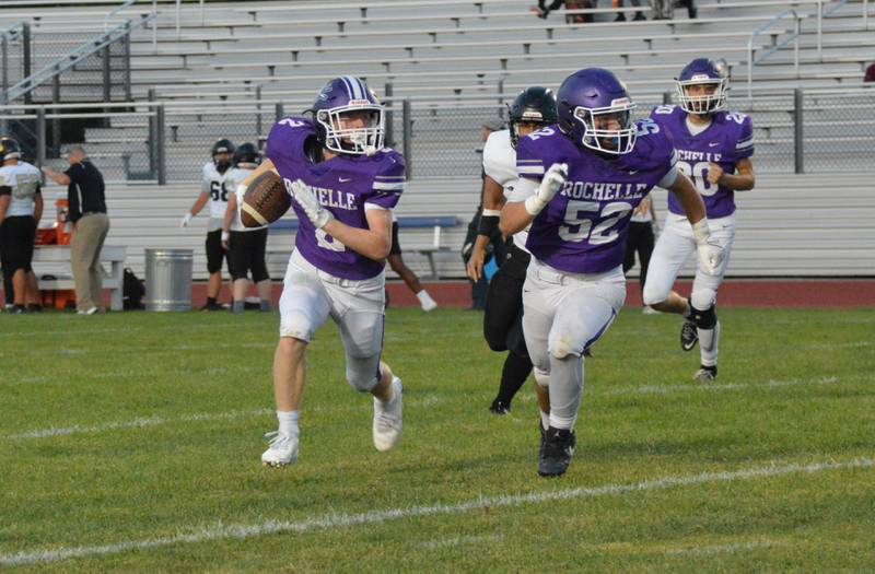 Rochelle's  Sebastian Albertson (52) leads running back Luke Chadwick (2) during a JV football game with Sycamore.