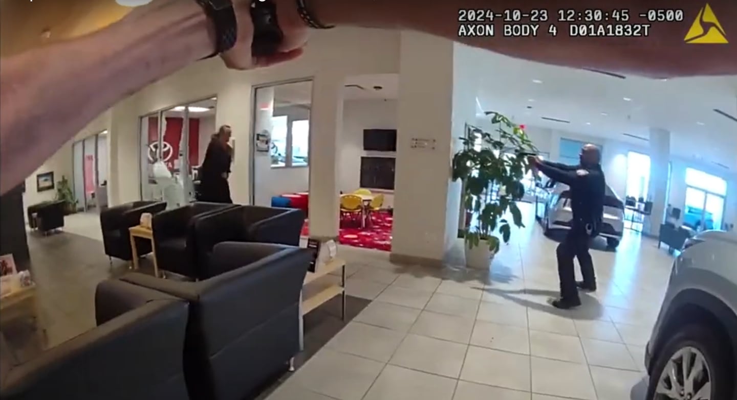 Body camera footage of DeKalb Police Officer Brian Bollow shows Bollow (foreground) and DeKalb Police Chief David Byrd (right) pointing a gun at Charles M. Tripicchio (left) as he brandishes two knives during an Oct. 23, 2024, attack at Brian Bemis Toyota of DeKalb, 1890 Sycamore Road. Byrd and Bollow shot Tripicchio, who survived, when he refused orders to put the weapons down. (Screenshot of footage provided by Illinois State Police)