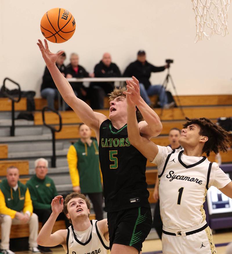 Crystal Lake South's Carson Trivellini grabs a rebound between Sycamore's Preston Picolotti (left) and Josiah Mitchell during their sectional semifinal game Tuesday, March 4, 2025, at Rochelle High School.