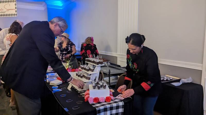 Elva Bores of Joliet serves a Shorewood Hugs chocolate ball attendee at the Elvitas Bakery Table at the Shorewood HUGS chocolate ball on Saturday, February 1, 2025, in Joliet.