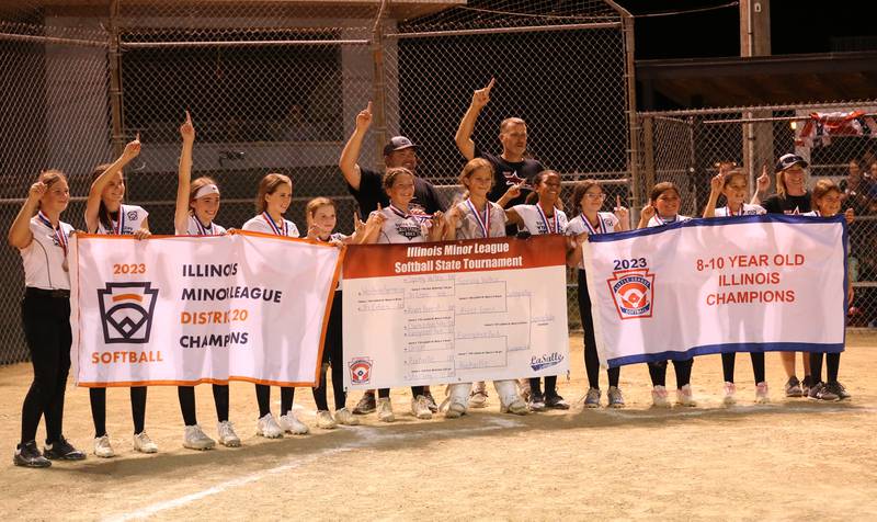 Members of the Spring Valley softball team pose with their championship banners after defeating Evergreen Park in the Minor League Softball State title on Thursday, July 27, 2023 at St. Mary's Park in La Salle.