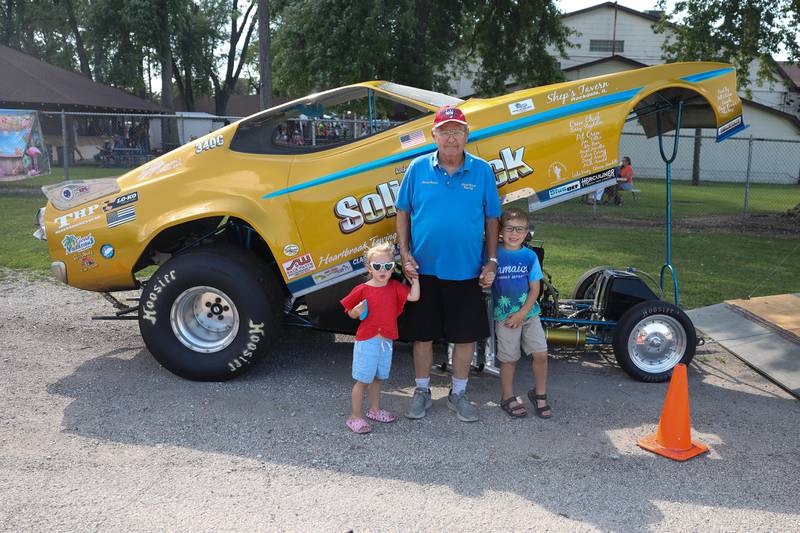 Rocky Ausec poses for a photo with his grandkids Sydney, left, and Dominic in front of his nostalgia funny car at the Crest Hill Lions Luau and Car Show on Sunday, Sept. 1, 2024 in Crest Hill.