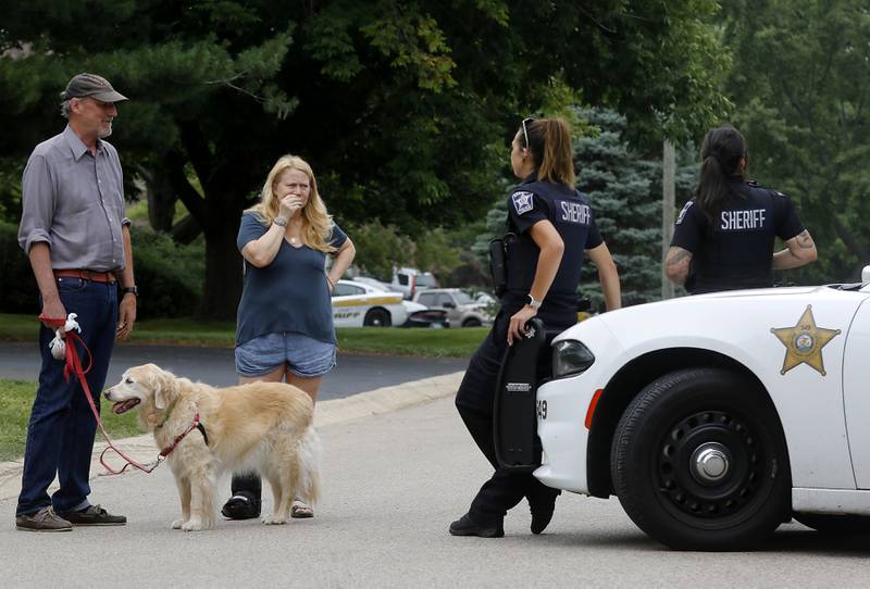 Fred and Betsy Brennan, with their dog Sophie, talk with officers from the McHenry County Sheriff Department in the 5800 block of Wild Plum Road in unincorporated Crystal Lake on Wednesday Aug. 9, 2023. Four people, including three females and a man described as the "aggressor," were killed. The Brennans live nearby.