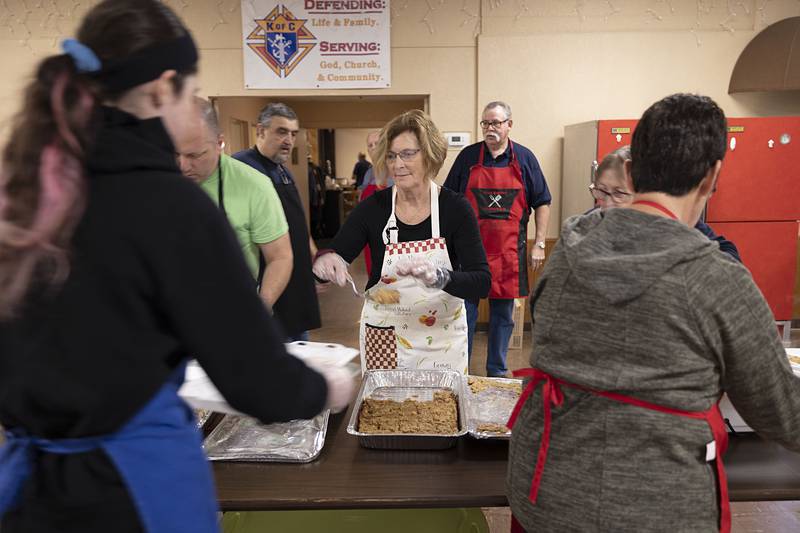 Julie Reglin dishes up the stuffing to a line of servers Thursday, Nov. 24, 2022.