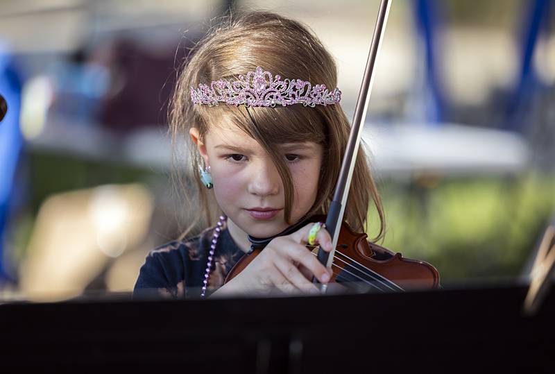 Etta Brinkerhoff, 8, plays a piece on the violin Wednesday, Aug. 21, 2024, at Dixon City Market. Brinkerhoff and sister Olive were showing off their skills learned from Viva! Performing Arts School, which had a booth at the market.