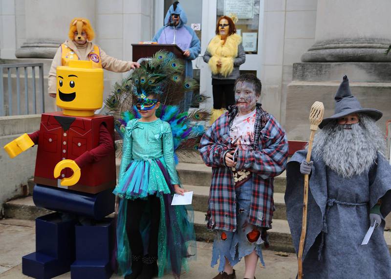 A Lego man, a peacock and a zombie walk wait on the courthouse steps.