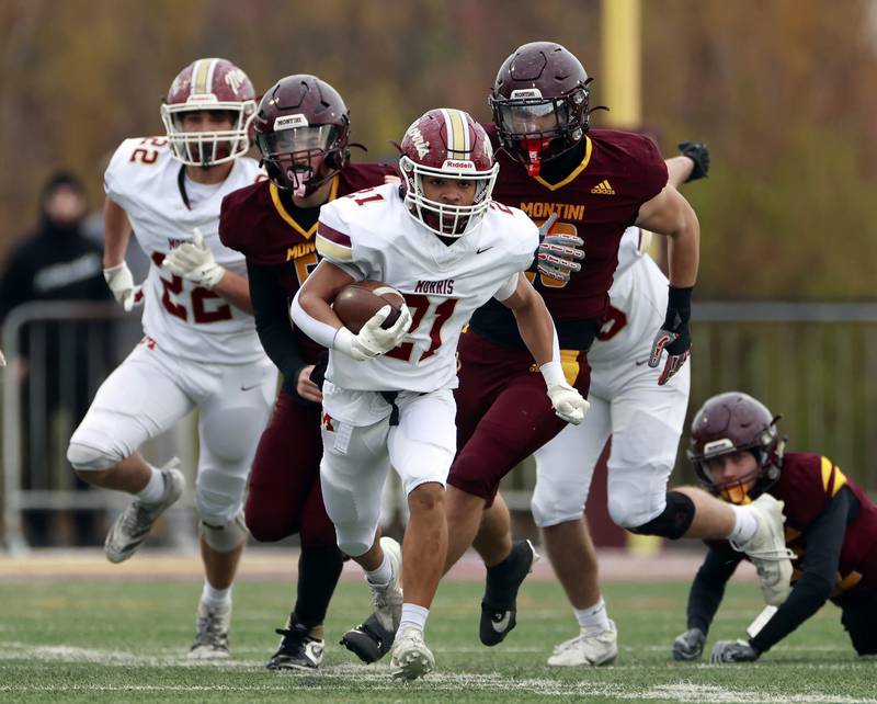 Morris' Anthony Smith (21) moves upfield with a host of Montini players in pursuit during the IHSA Class 4A semifinals football playoff game Saturday, Nov. 22, 2025 in Lombard.