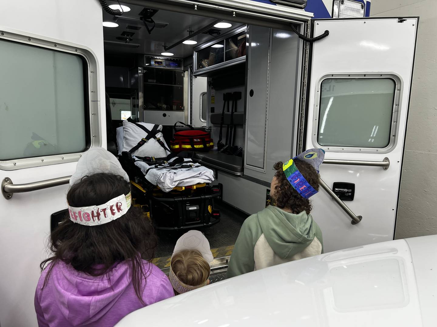Bureau County Special Schools students Ameliah Sedam, Mikey Stedman, and Amiyah Coe examining a Tiskilwa Fire Department ambulance