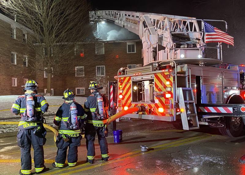 Three DeKalb firefighters stand ready to aid crews responding to an apartment fire on Sunday, Dec. 22, 2024, at 1024 W. Hillcrest Drive in DeKalb. The blaze, just before Christmas, is expected to impact multiple residents in the three-building complex.