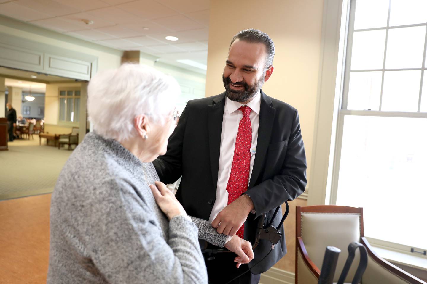 Executive Director Julio Macias talks with resident Margot Burgh at Covenant Living at the Holmstad in Batavia. Macias began working as a dishwasher at the facility when he was 16 years old.