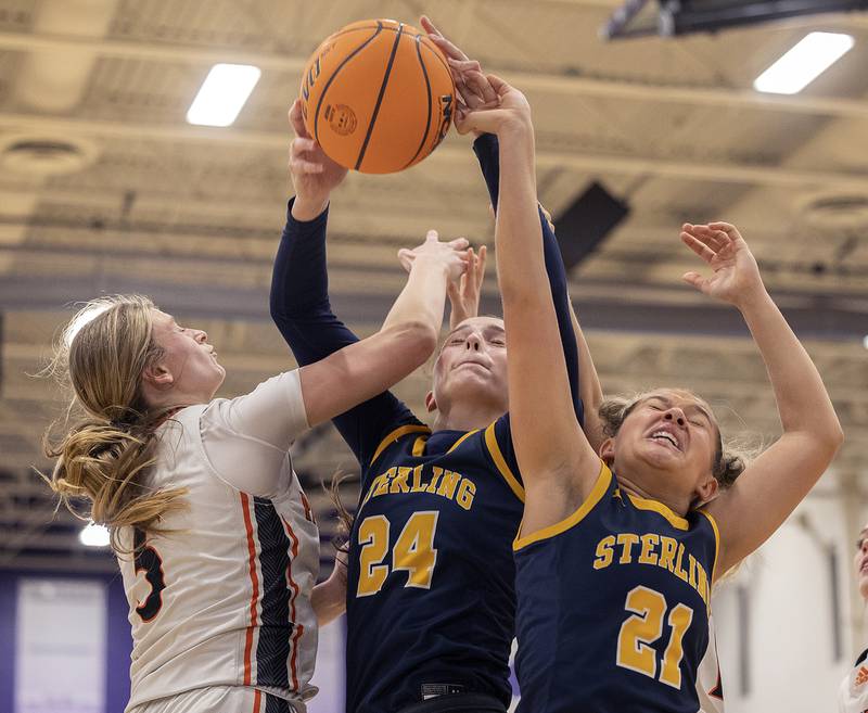 Sterling’s Madison Austin (middle) and Jae James fight for rebound against Washington’s Rebecca McDougall Monday, March 3, 2025, during the 3A Supersectional at Rochelle High School.
