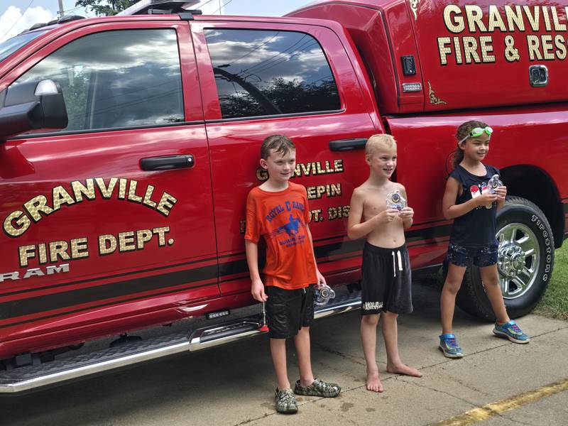(From Left) Brayden Cox (second), Kaden Quick (first) and Anna Bell (third) show off their water fight trophies on Saturday, Aug. 3, 2024, during Granville Days at Hopkins Park.