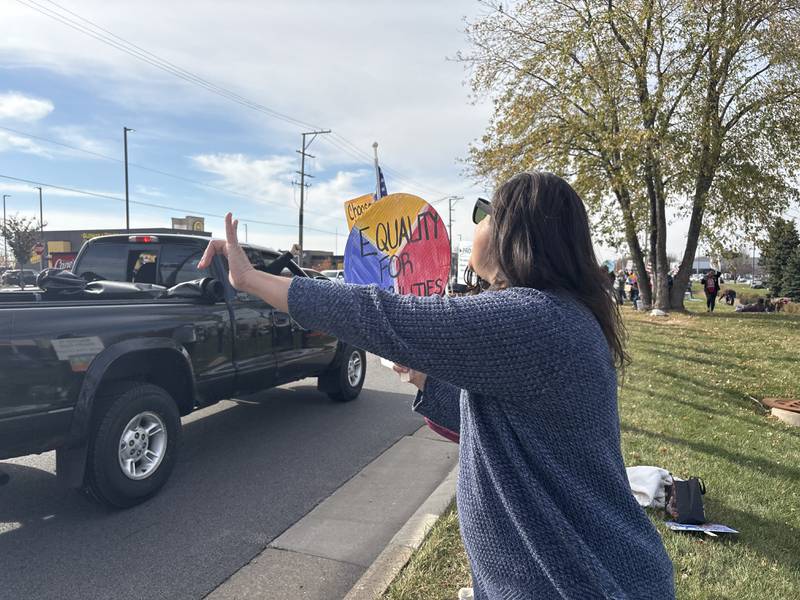 Grace Kozlowski gives a "rock on" sign while someone gives the thumbs-down at a pro-Harris rally Nov. 2, 2024 in Crystal Lake.