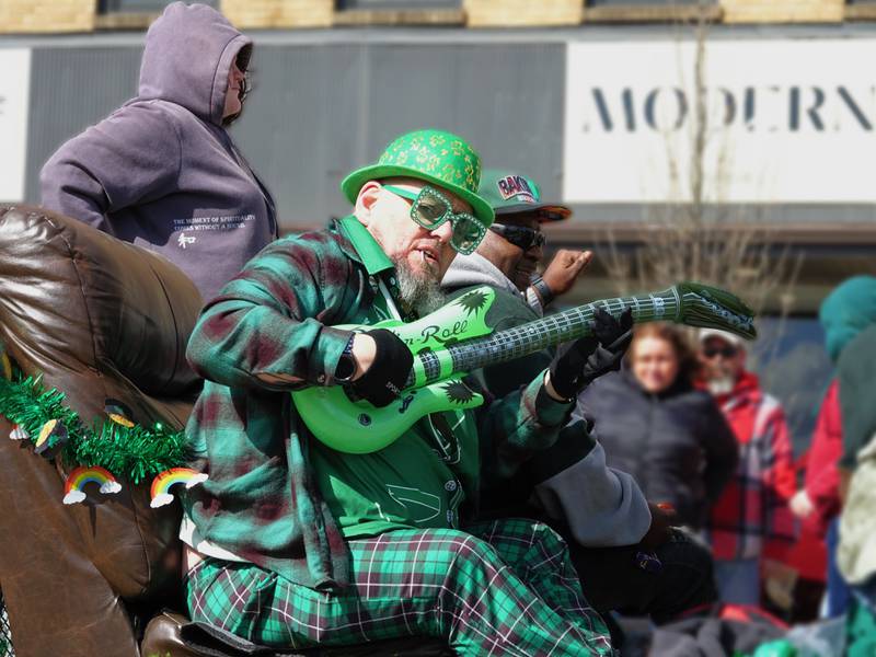 A St. Patrick Day parade participate holds an inflatable guitar Saturday, March 9, 2024, on First Street in La Salle.