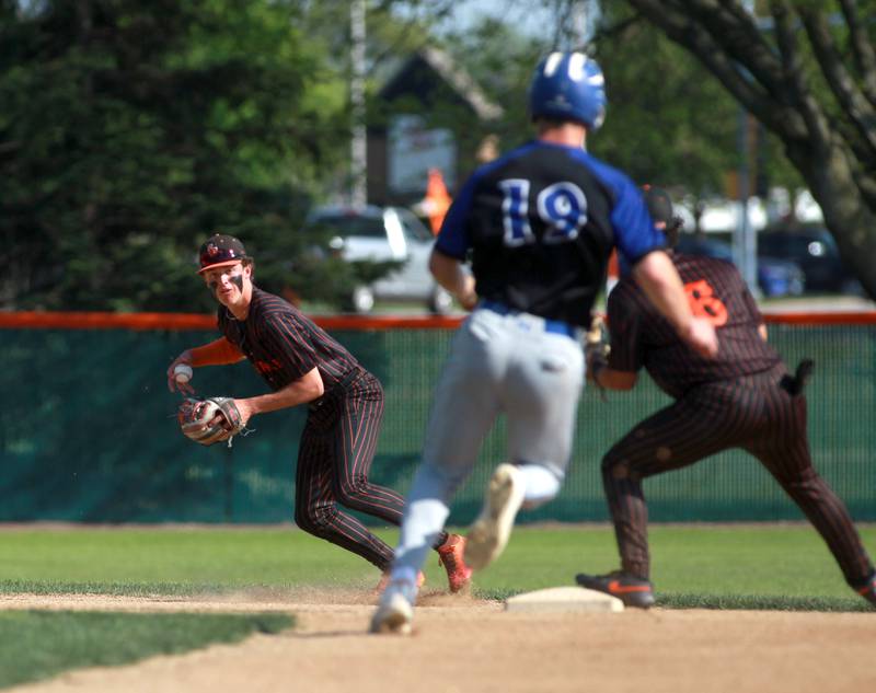 St. Charles East's James Feigleson looks to throw to first as Geneva's Noah Hallahan slides safely into second base during a game on Tuesday, May 13, 2024 in St. Charles.