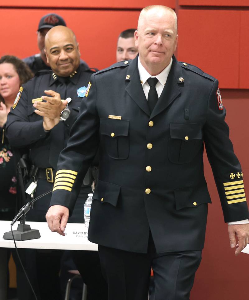 DeKalb Police Chief David Byrd applauds as acting DeKalb Fire Chief Michael Thomas walks up to be sworn in as the city's new full-time fire chief Monday, April 11, 2022, during the DeKalb City Council meeting at the library. Thomas has been serving as the acting chief since the retirement of former chief Jeff McMaster in November.