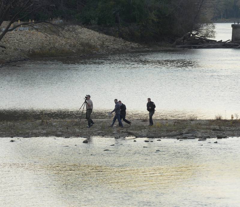 Law enforcement officers examine the area near where a body was found in the Rock River, near the Peoria Avenue Bridge on Tuesday afternoon. The body appeared to be found near the edge of a sand bar in shallow water.