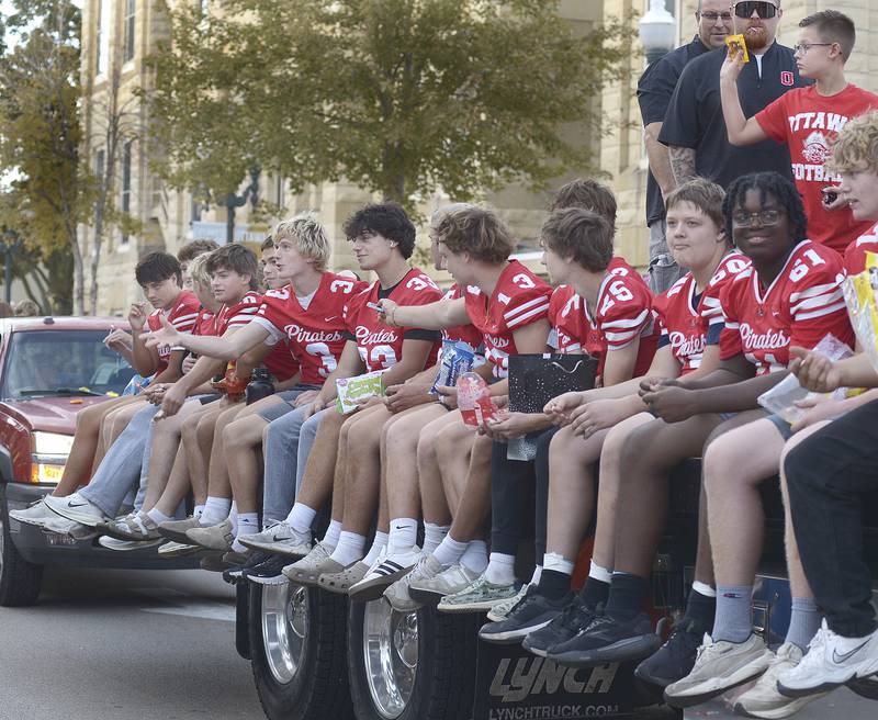 The Ottawa High Football team toss candy treats to those along the parade route Wednesday evening during the school’s annual Homecoming Parade in Ottawa.