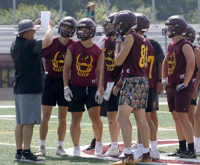 Richmond-Burton coach Mike Noll shows a play to his players during a 7 on 7 football practice Monday, July 14, 2025, at Richmond-Burton High School, with teams from Crystal Lake Central.  Grayslake Central and Mundelein.